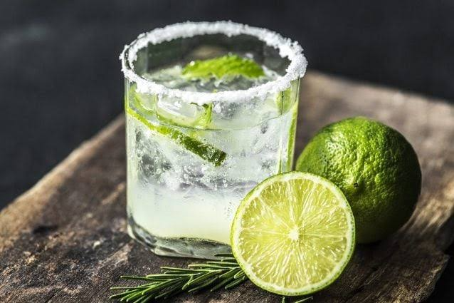 Refreshing lime mocktail with mint, ice, and a salted rim, served with fresh lime slices on a rustic wooden board.