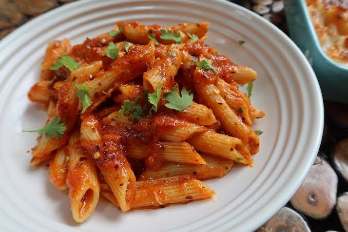 Corner Cafe pasta featuring penne tossed in rich tomato sauce, herbs, and spices, served on a white plate.